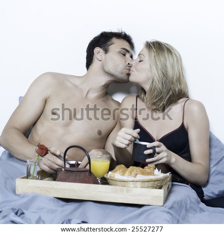 beautiful young caucasian couple in a bed on isolated background having breakfast in bed