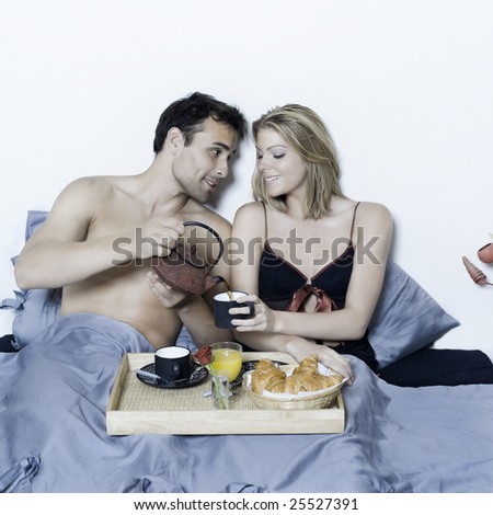 beautiful young caucasian couple in a bed on isolated background having breakfast in bed