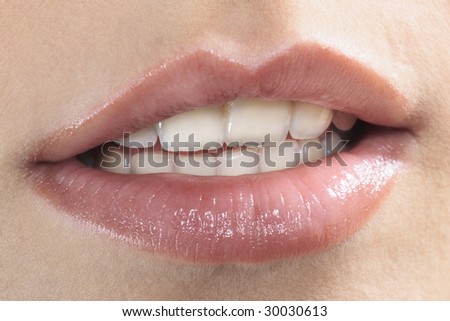 studio shot close up detail of the face of a beautiful young women with perfect lips mouth and teeth smiling