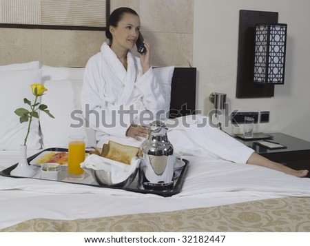 beautiful calm and serene woman in palace hotel room having her breakfast phoning