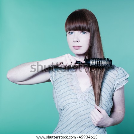 studio portrait of a young woman on isolated background brushing hai