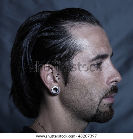 urban stylish caucasian young man with pierced ears and piercing studio portrai