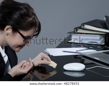beautiful brunette business woman at her desk trying to trap her computer mouse with cheese