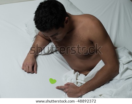 beautiful caucasian young man in a bed with a love note stick