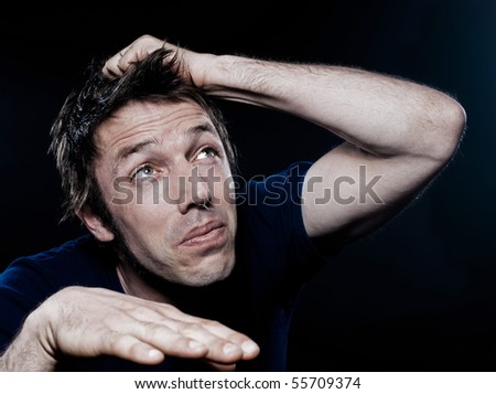 studio portrait on black background of a funny expressive caucasian man looking up scare