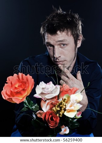 studio portrait on black background of a funny expressive caucasian man offering flowers sh