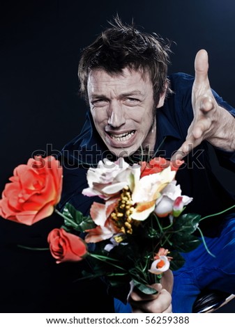 studio portrait on black background of a funny expressive caucasian man offering flowers ange
