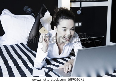 beautiful caucasian woman happy holding credit card internet shopping in a bedroom
