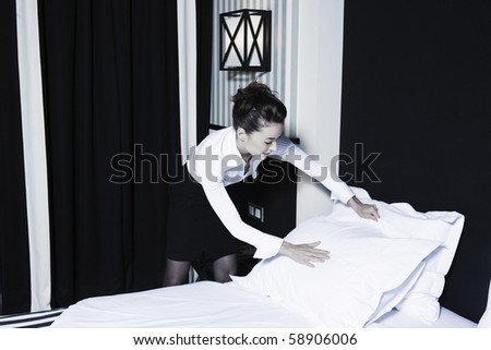 beautiful caucasian woman maid make bed in a hotel bedroom