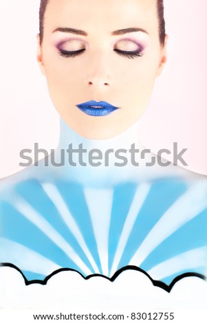 Closeup portrait of an artistic woman painted with blue representing the sky isolated on pink background