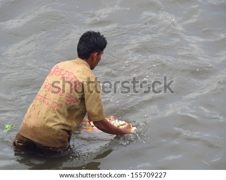 PUNE, INDIA Ã¢Â?Â? SEPTEMBER 18, 2013 : An Indian lifeguard traditionally submerges an idol of lord Ganesh in a river as a tradition of ending the Ganapati festival