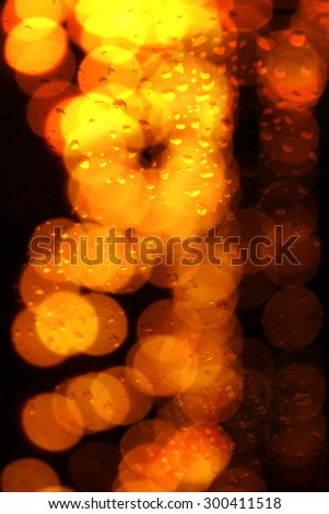 An abstract background of a glass pane with droplets with a droplet of festive lights