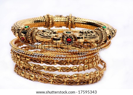 A conceptual image of a jeweled bangle on the top of other bangles with simple pattern on a white fabric, depicting the qualities of a leader.