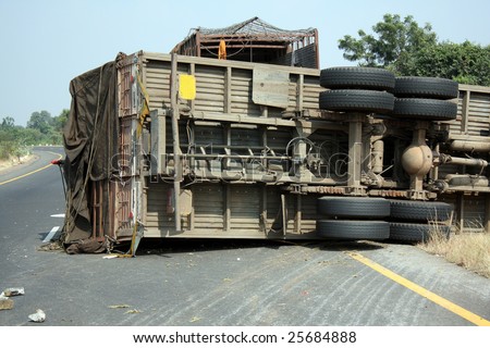 A view of the rear wheels of a skidded overturned truck on an highway in an accident.