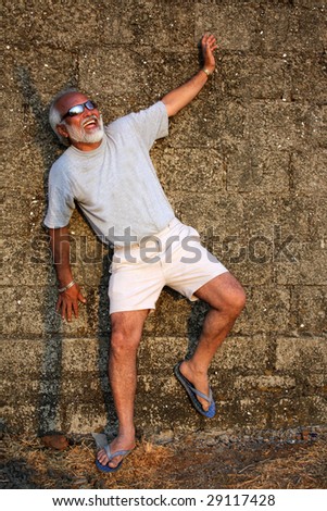 A handsome senior Indian man modeling giving a pose against an old wall.