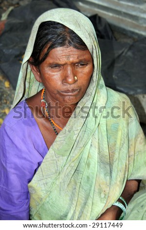A portrait of a very poor woman from India who makes a living either in making small objects for sale or begging.