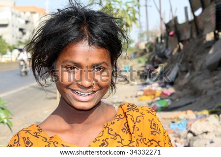 A portrait of a happily smiling poor Indian teenager, on the streetside.