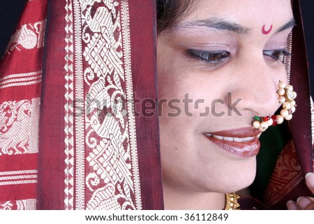 A portrait of traditional Indian woman in a green sari wearing a nosering.