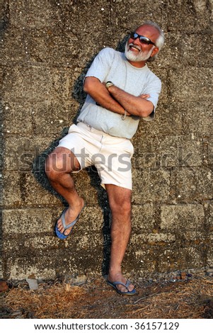 A handsome senior Indian man modeling giving a pose against an old wall.