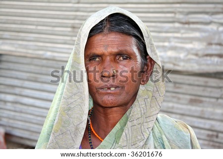 A portrait of a very poor woman from India who makes a living either in making small objects for sale or begging.