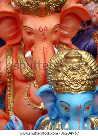 A religious background with an abstract view of the beautiful idols of the Hindu elephant god - Ganesha in blue and orange colors.