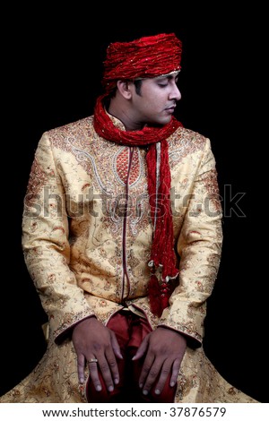 A royal young Afghan man in prayers, on black studio background.