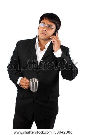 An Indian businessman talking on the cellphone during the coffee break, on white studio background.