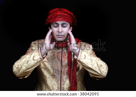 A royal young Afghan man in prayers, on black studio background.