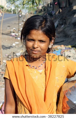 A portrait of a poor Indian teenage girl in a traditional attire, on the roadside.