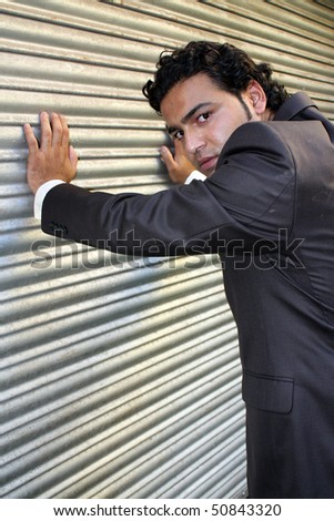 A stylish angry businessman posing near a shutter.