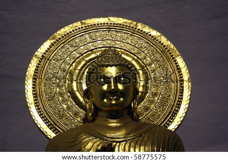 A portrait of a golden statue of a meditating golden Buddha.
