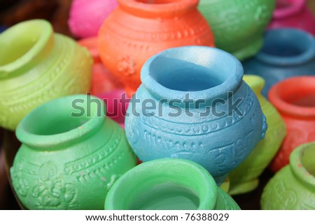 Small clay pots in various colors with religious text inscribed for Diwali festival celebration rituals in India.