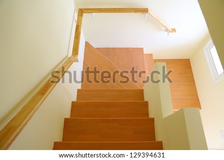 Wooden staircase and handrail leading to the upper, low level. Interior design.