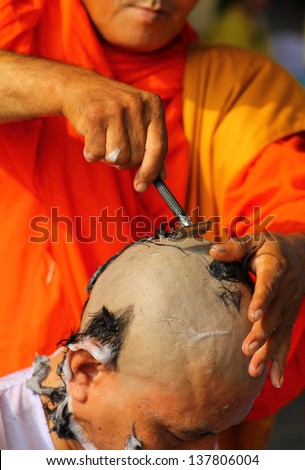 Thai man gets his head shaved by a monk during a Buddhist ordination ceremony