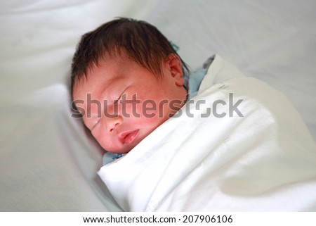 newborn infant asleep in the blanket in delivery room