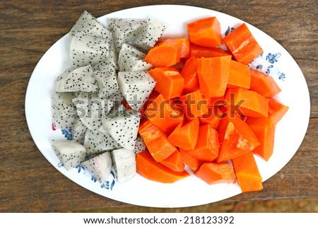 Delicious Chopped Ripe Papaya and dragon Fruit in dish on wood background
