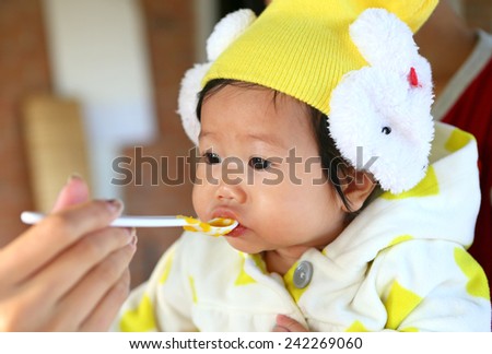 Close up Five month old South East Asian Thai baby girl being spoon fed