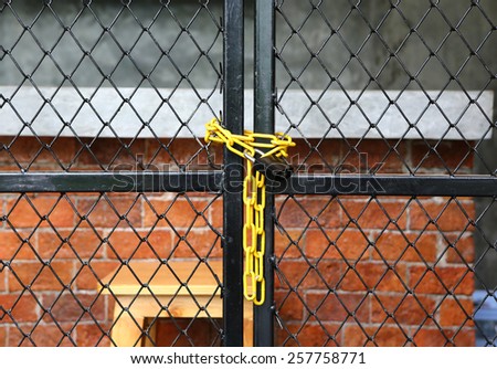Yellow chain link fence and metal door with lock