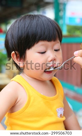 Little Asian baby eating rice by stainless spoon