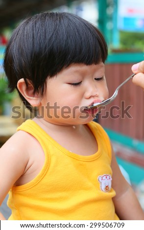 Little Asian baby eating rice by stainless spoon