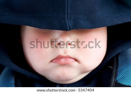 cute baby boy sleeping in car seat, eyes covered with cape