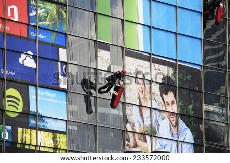 PARIS, FRANCE - SEPTEMBER, 2, 2014. Facade of a corporate office building in the financial center La Defense, Paris. Two people working at advertising at the building.