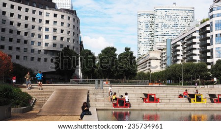 PARIS, FRANCE - SEPTEMBER, 1, 2014. Corporate office buildings in the business park of La Defense in Paris.People are lunching and relaxing around the tables near the bassin.