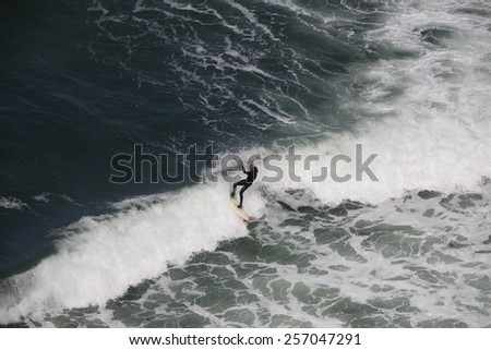 ETRETAT, FRANCE - AUGUST 23, 2010: man surfing at the waves of the Nort-Sea for Etretat, Normandy, France