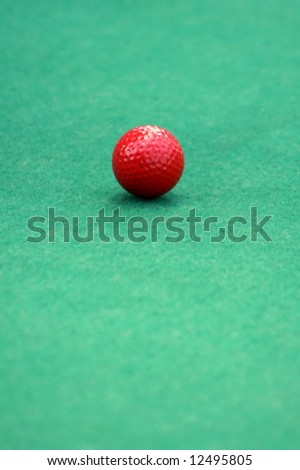 Red golf ball on a mini golf putting green