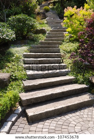 A stone staircase winds up a steep landscaped garden path, with a tiled step at the bottom