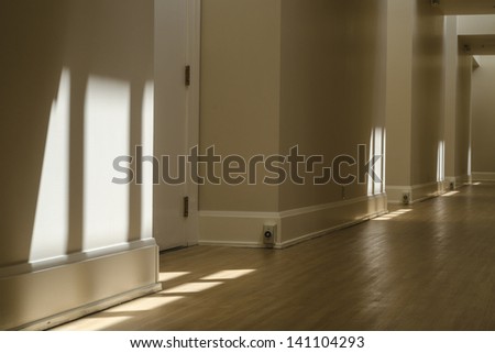 A long hallway disappears into the distance as sun filters down in patterns from the skylights above