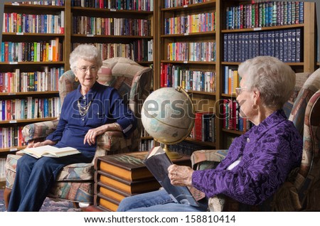 Two elderly women talk in a comfortable  library in a retirement and assisted living residence.