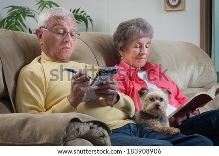 An older couple relaxes together with their lap dog, a cute little Brussels Griffon, keeping them company.