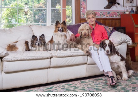 A formal portrait of a ninety year old woman with her four dogs in her tastefully decorated living room.horizontal